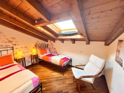 a bedroom with two beds and a chair and a window at Casa Lory in Bellagio