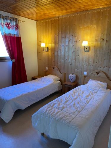 deux lits dans une chambre aux murs en bois dans l'établissement Location de la cascade 8 personnes, à Besse-et-Saint-Anastaise