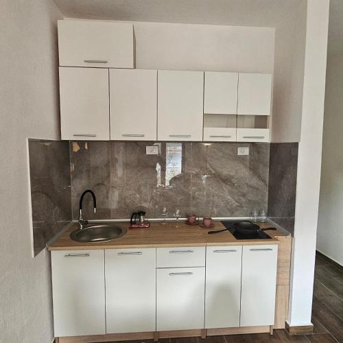 a kitchen with white cabinets and a sink at InesAna in Kotor
