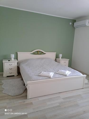 a bedroom with a white bed and two night stands at Къща за гости НИКА in Kavarna
