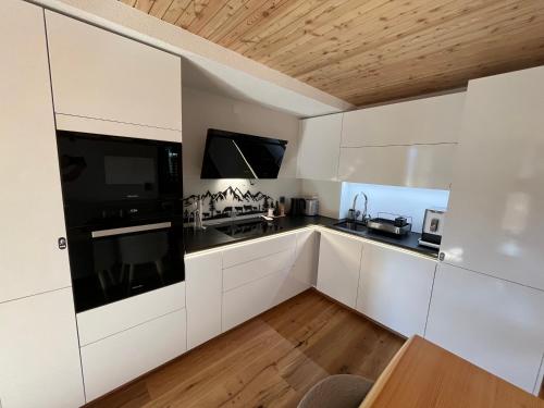 a kitchen with white cabinets and black appliances at Evolène Panorama- Renovated Apartment with Dent Blanche View 2-4 persons in Evolène