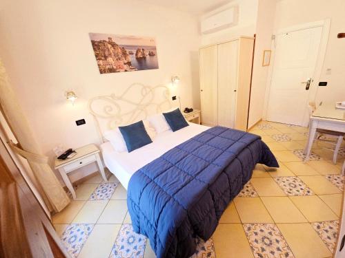 a bedroom with a bed with a blue comforter at Hotel Cala Marina in Castellammare del Golfo