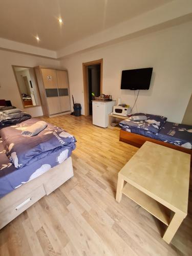 a room with two beds and a table and a tv at Hotel Room Apartment in Skopje
