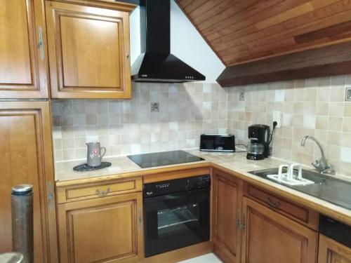 a kitchen with wooden cabinets and a stove top oven at Location de la cascade 8 personnes in Besse-et-Saint-Anastaise