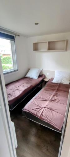 deux lits dans une petite pièce avec une fenêtre dans l'établissement mobil home Eleganzia domaine de kerlann, à Pont-Aven