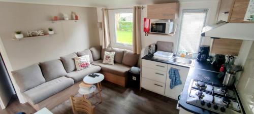 un petit salon avec un canapé et une cuisine dans l'établissement mobil home Eleganzia domaine de kerlann, à Pont-Aven