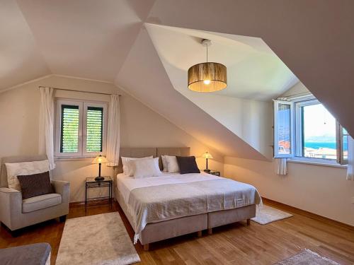 a bedroom with a bed and a chair and windows at House Bianca Brac - New Listing - Experienced host in Postira