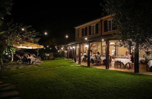 a group of people sitting at tables in a yard at night at Relais Borgofasceo in Ortovero