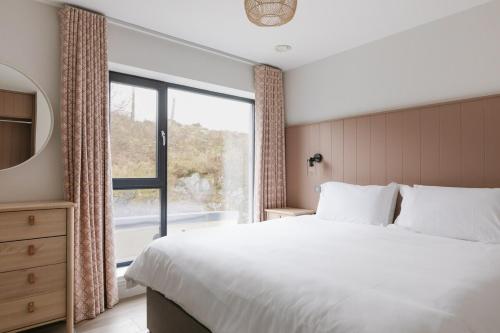 a bedroom with a large bed and a window at Tullagh at Ballyliffin Beach Houses, Pollan Bay in Ballyliffin