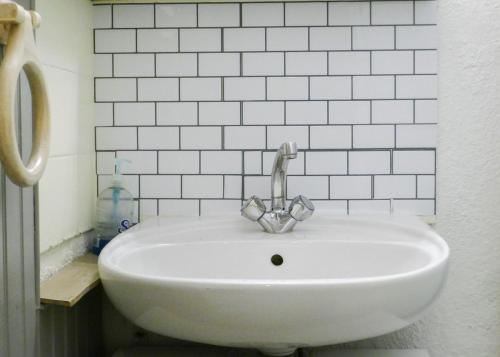 La salle de bains est pourvue d'un lavabo blanc et d'un robinet. dans l'établissement Appart au Lac d'Aiguebelette et Montagne, à Aiguebelette-le-Lac