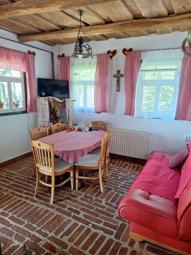 a dining room with a table and a red couch at Jurina Hiža in Beletinec
