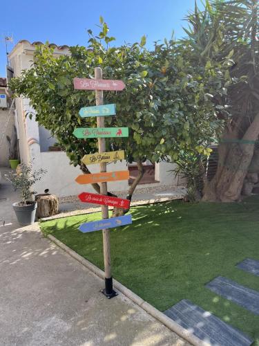 a wooden directional sign in front of a tree at L Abri-côtier Appartements in Saintes-Maries-de-la-Mer