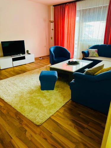 a living room with a couch and a table and blue chairs at El&Ma Apartment - 3 bedroom apartment with balcony close to Sarajevo City Center, Sunnyland - free parking in Sarajevo