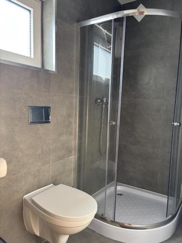 a bathroom with a toilet and a glass shower at Domki letniskowe in Ostrów Warcki