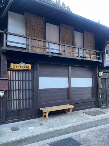 a bench sitting in front of a building with a balcony at Matsumuraya Koma in Shiojiri