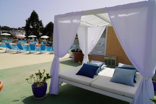 a couch under a canopy next to a pool at Hotel Parco Delle Agavi in Ischia
