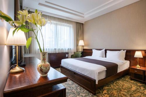 a hotel room with a bed and a vase with flowers at Hotel & Spa PALIĆ RESORT in Palić