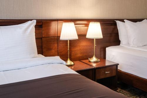 two beds in a hotel room with two lamps at Hotel & Spa PALIĆ RESORT in Palić