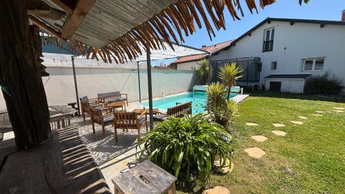 un patio avec une table et des chaises et une piscine dans l'établissement Villa TIKI BAR piscine chauffée 4 chambres, à Labenne