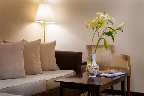 a living room with a couch and a vase with flowers on a table at Hotel & Spa PALIĆ RESORT in Palić