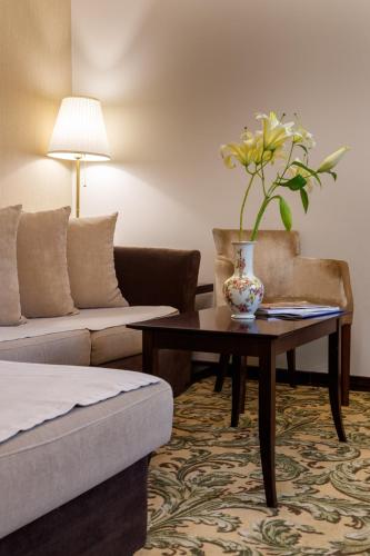 a living room with a table with a vase of flowers on it at Hotel & Spa PALIĆ RESORT in Palić