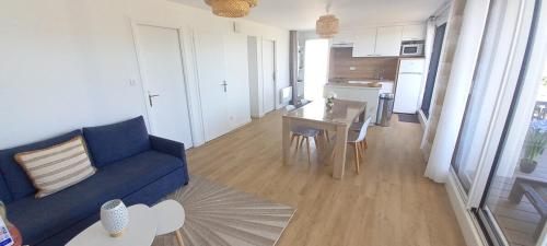 un salon avec un canapé bleu et une table dans l'établissement Bel appartement, grande terrasse côté mer Kerroc'h, à Ploemeur