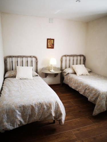 a bedroom with two beds and a table with a lamp at El Mirador de Abionzo in Abionzo