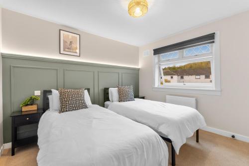 two beds in a bedroom with a window at Cosy Corner at Innerleithen in Innerleithen