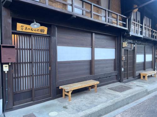 a building with two benches in front of a store at Matsumuraya Koma in Shiojiri