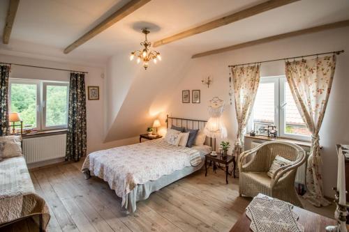 a bedroom with a bed and a chair and windows at Dom pod Skrzydłami in Gawliki Wielkie