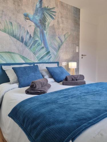 une chambre avec un lit bleu avec des serviettes dessus dans l'établissement Maison design en bord de lac, à Saint-Jean-de-Monts
