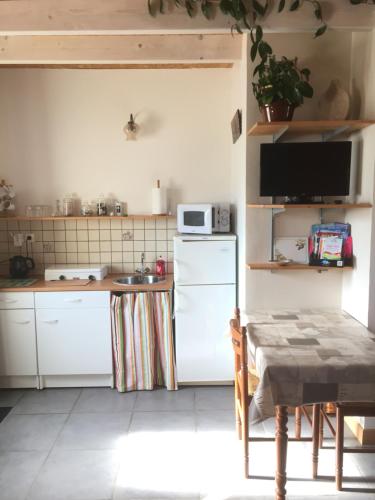 une cuisine avec un réfrigérateur blanc et une table dans l'établissement Le Petit Baron, à Châtillon-sur-Cher