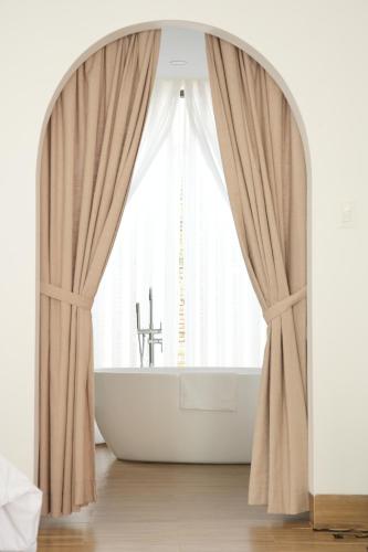 a bathroom with a white tub and a window at An Home - Garden Homestay in Plei Brel (2)