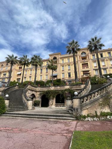 un grand bâtiment avec des palmiers devant dans l'établissement Parc Continental Apartment with sea view, à Cannes