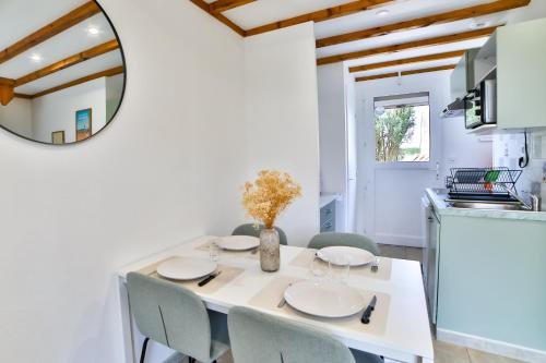a dining room with a white table and chairs and a mirror at Maison des dunes in Erdeven