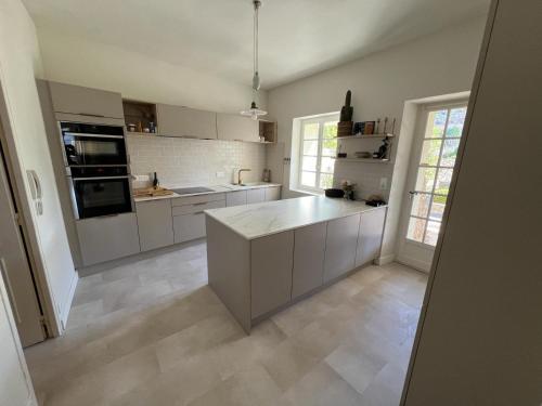 une grande cuisine avec des armoires et des appareils blancs dans l'établissement Mas La Magnanerie du Ventoux, à Malaucène