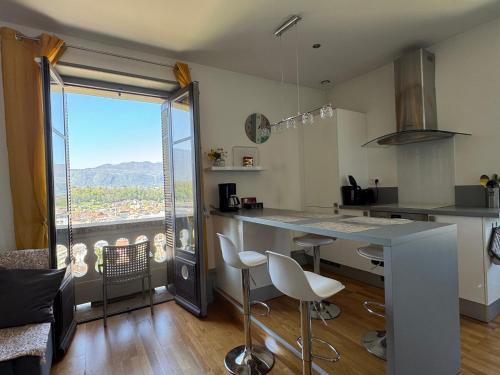 une cuisine avec un comptoir avec des chaises et une grande fenêtre dans l'établissement Superbe T2 lumineux et confortable avec prestations de qualité à Aix-les-Bains ! - FR-1-555-46, à Aix-les-Bains