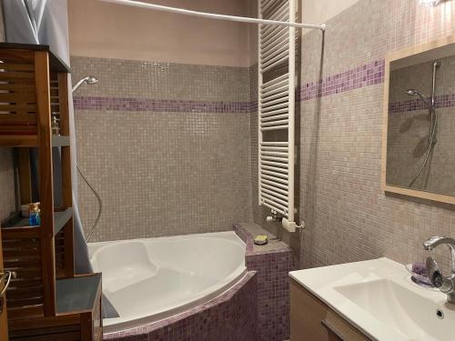 une salle de bain avec une baignoire et un lavabo dans l'établissement Maison de village, à Labastide-dʼAnjou