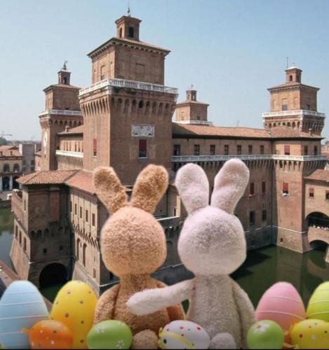two stuffed rabbits sitting in front of a castle at Hotel Fondo Catena in Ferrara