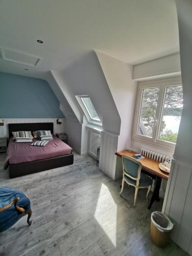 une chambre avec un lit, un bureau et des fenêtres dans l'établissement Les pieds dans l'eau, à Saint-Malo