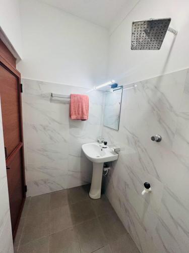 a white bathroom with a sink and a shower at Humming Birds Suites in Jaffna