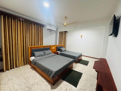 a bedroom with two beds and a window at Humming Birds Suites in Jaffna
