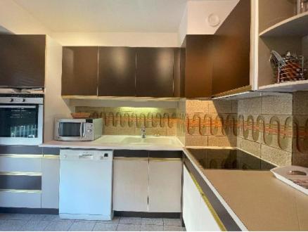 La cuisine est équipée de placards bruns et d'un réfrigérateur blanc. dans l'établissement Centre cannes Galia 210 m2, à Cannes