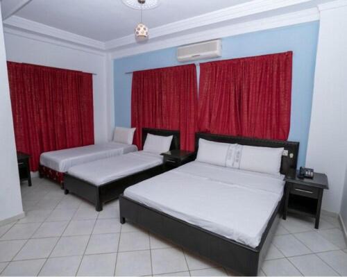 a bedroom with two beds and red curtains at Hotel OUM EL FADL in Fkih Ben Salah