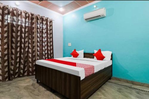 a bedroom with a bed with red pillows at Hotel O Smart City Guest House in Ballabgarh