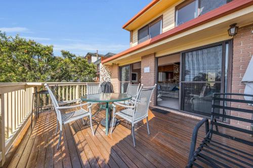 a wooden deck with a table and chairs on it at Waves on Winnunga in Pambula Beach