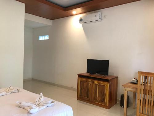 a room with two beds and a tv on a table at Pohon Purba Resort & Restaurant in Labuan Lombok