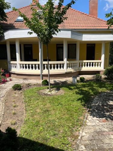 a yellow house with a bench in the yard at Vidéki Vendégház in Doboz