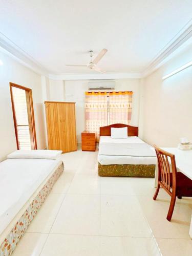 a bedroom with two beds and a chair in it at Maya Eco Guest House in Dhaka