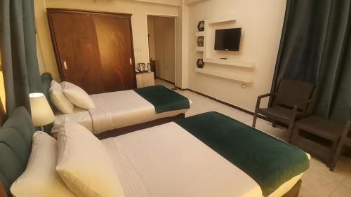 a hotel room with two beds and a television at Fanara Apartments Armed Forces in Fayed